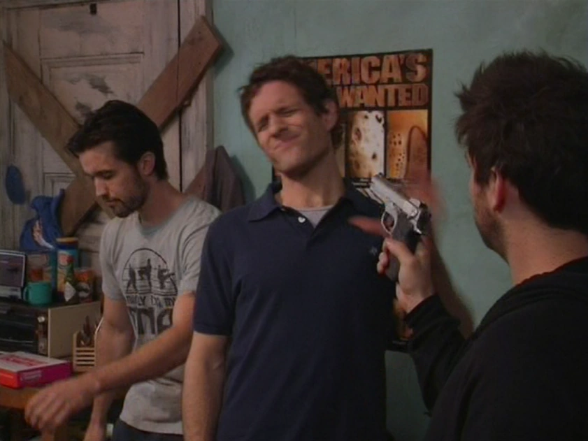 Still from It's Always Sunny S01E05: Charlie turns the gun on Dennis and Mac